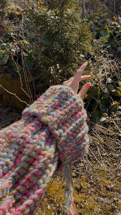 Hand wearing a colorful knitted sleeve against a natural background