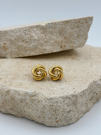 Gold knot stud earrings displayed on natural stone, minimalist and elegant jewelry design perfect for everyday or special occasions