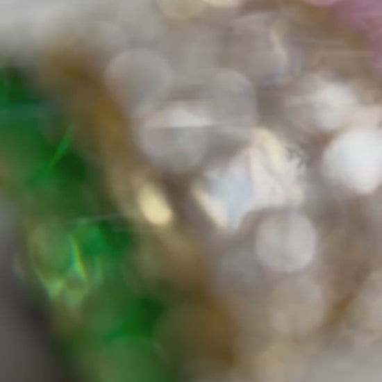 green, pink and clear zirconia stone ring on a concrete plate with soft sunlight, female hand is wearing the rings while displaying the