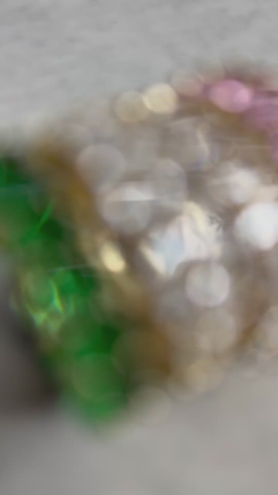 green, pink and clear zirconia stone ring on a concrete plate with soft sunlight, female hand is wearing the rings while displaying the