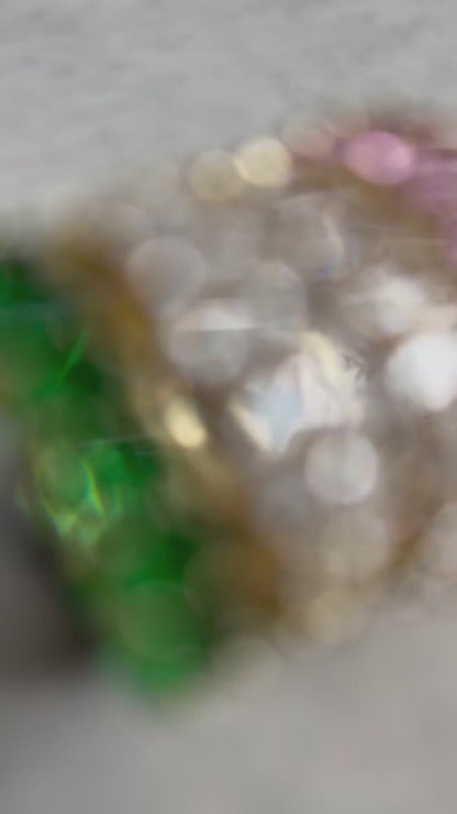 green, pink and clear zirconia stone ring on a concrete plate with soft sunlight, female hand is wearing the rings while displaying the